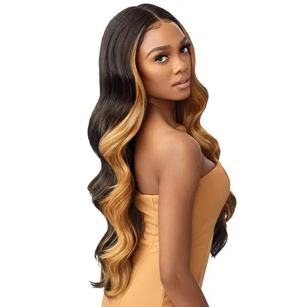 Longue Perruque Lace Front ondulée avec tulle HD Transparente. Confectionnée avec ches cheveux synthétiques, cette perruque résiste à la chaleur. Modèle présenté en châtain clair avec mèches blondes DFRR Amber Sunset.